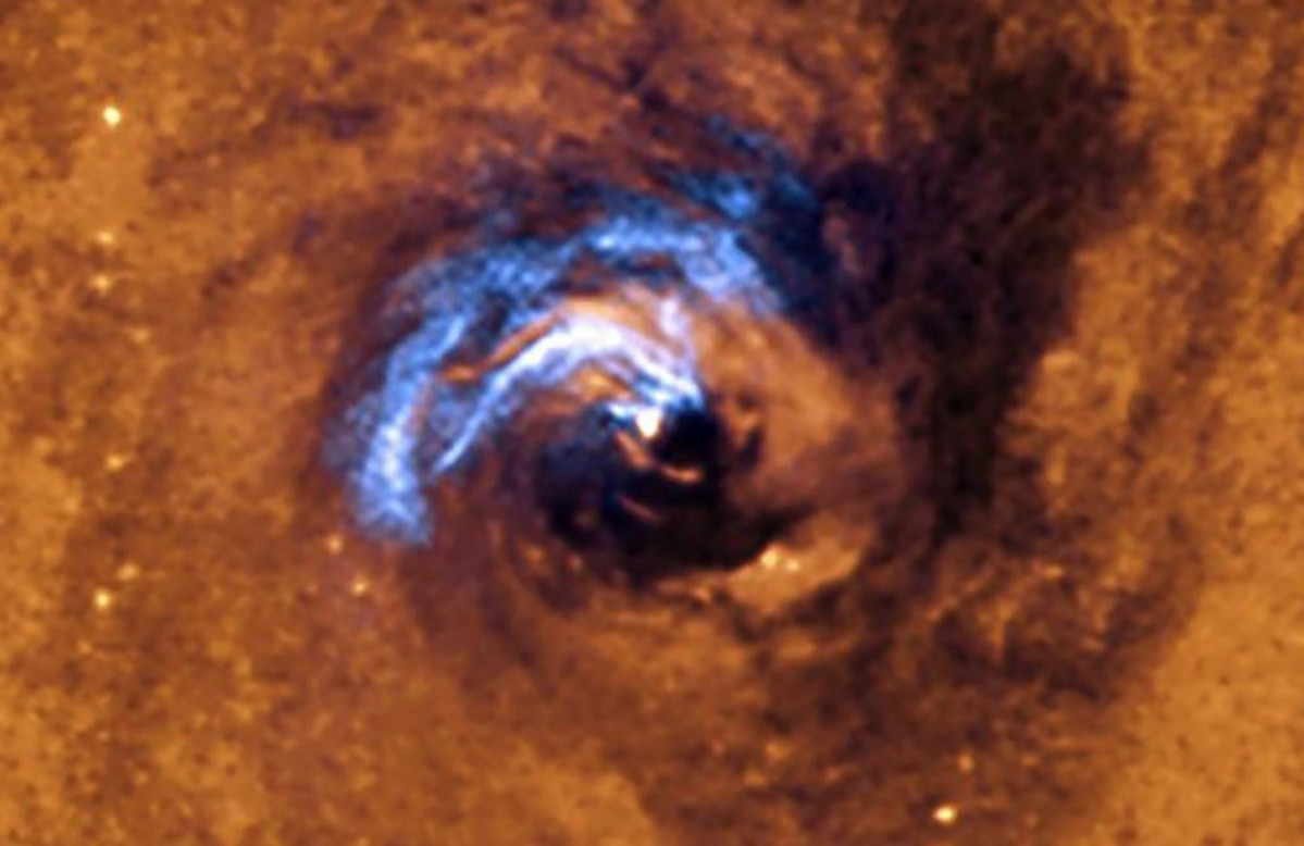 La imatge mostra el procés d'alimentació nuclear d'un forat negre a la galàxia NGC 1566, i com els filaments de pols, que envolten a l'nucli actiu, queden atrapats i giren en espiral al voltant de l'forat negre fins que se'ls empassa.
