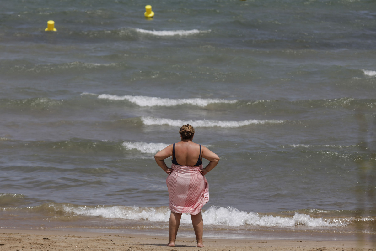 Una dona a la platja de la Malva-rosa en un dia d'alerta roja per altes temperatures, a 12 de juliol de 2021, a València, Comunitat Valenciana (Espanya). Les províncies d'Alacant, València i Múrcia tenen aquest dilluns avisos de nivell vermell (risc extrem