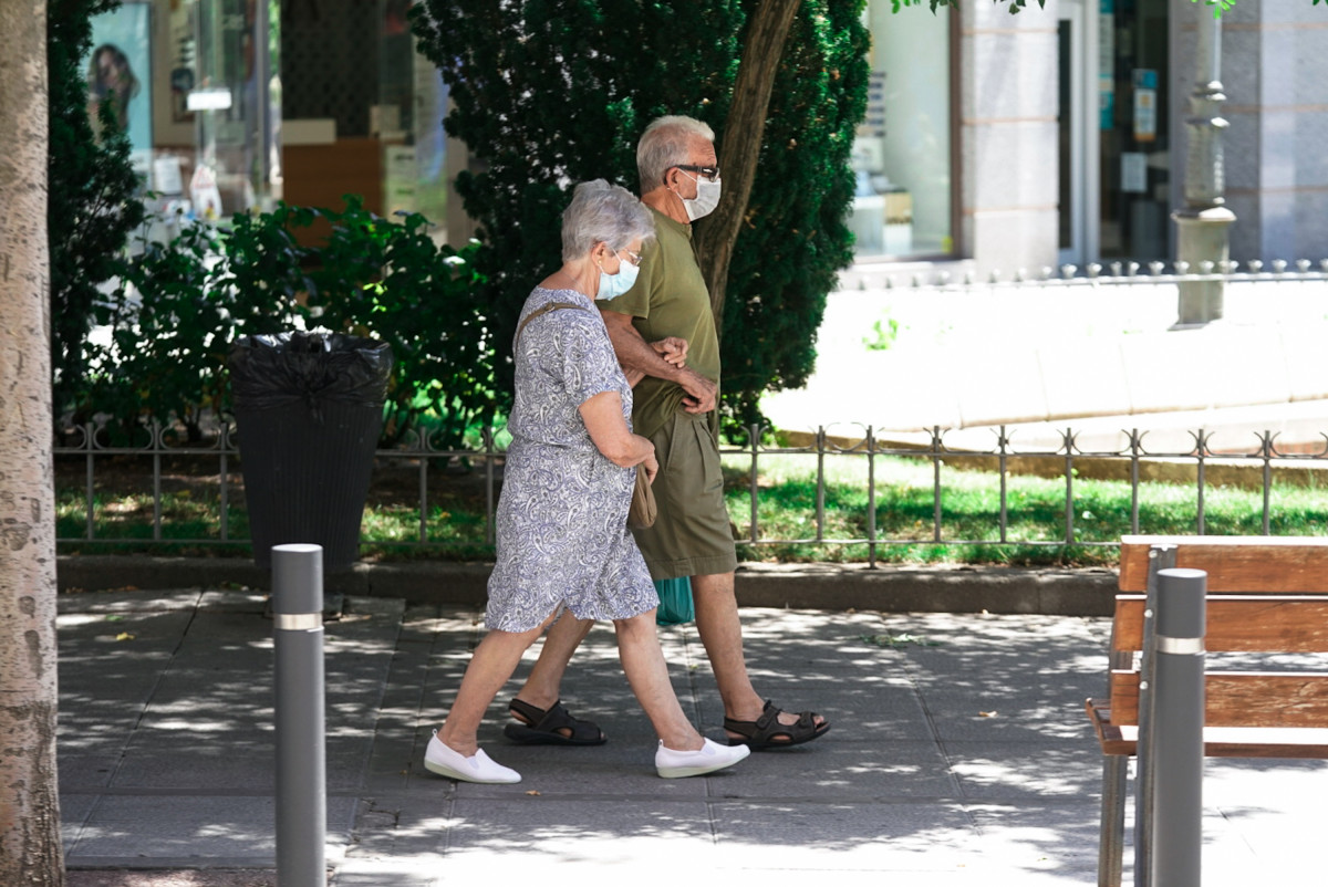 Una parella d'avis amb mascareta camina pel carrer agafada de el braç, a 27 de juliol de 2021, a Madrid, (Espanya).