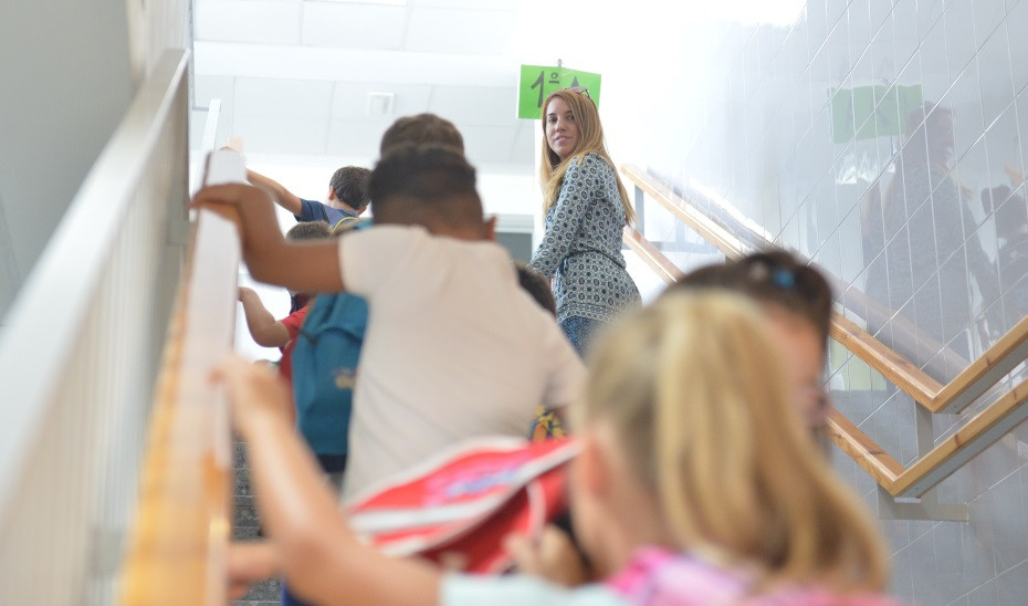 Arxiu - Nens de Primària es dirigeixen a la seva aula amb una treballadora del centre escolar