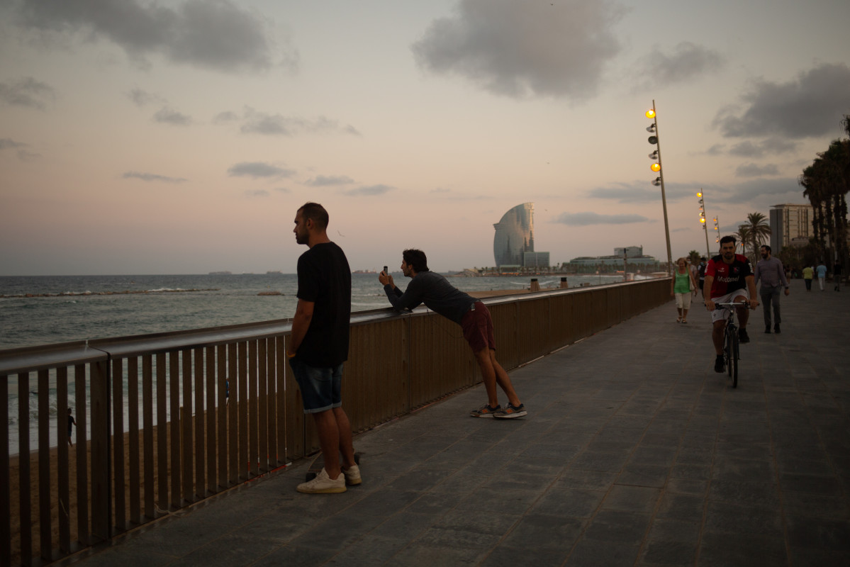 Dos homes miren el paisatge davant de la platja de la Barceloneta, a 4 d'agost de 2021, a Barcelona, Catalunya (Espanya).