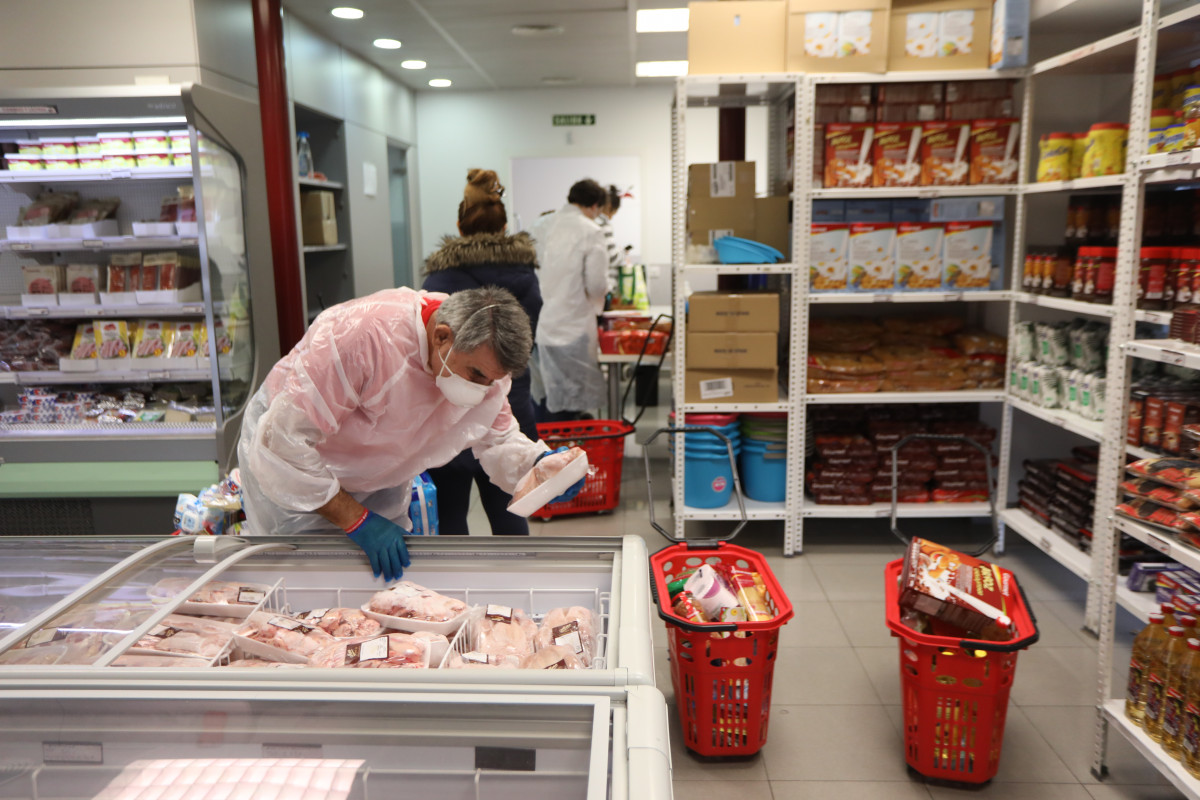 Arxiu - Un voluntari manipula els aliments d'un refrigerador a l'interior de l'economat solidari de Càritas a Madrid.