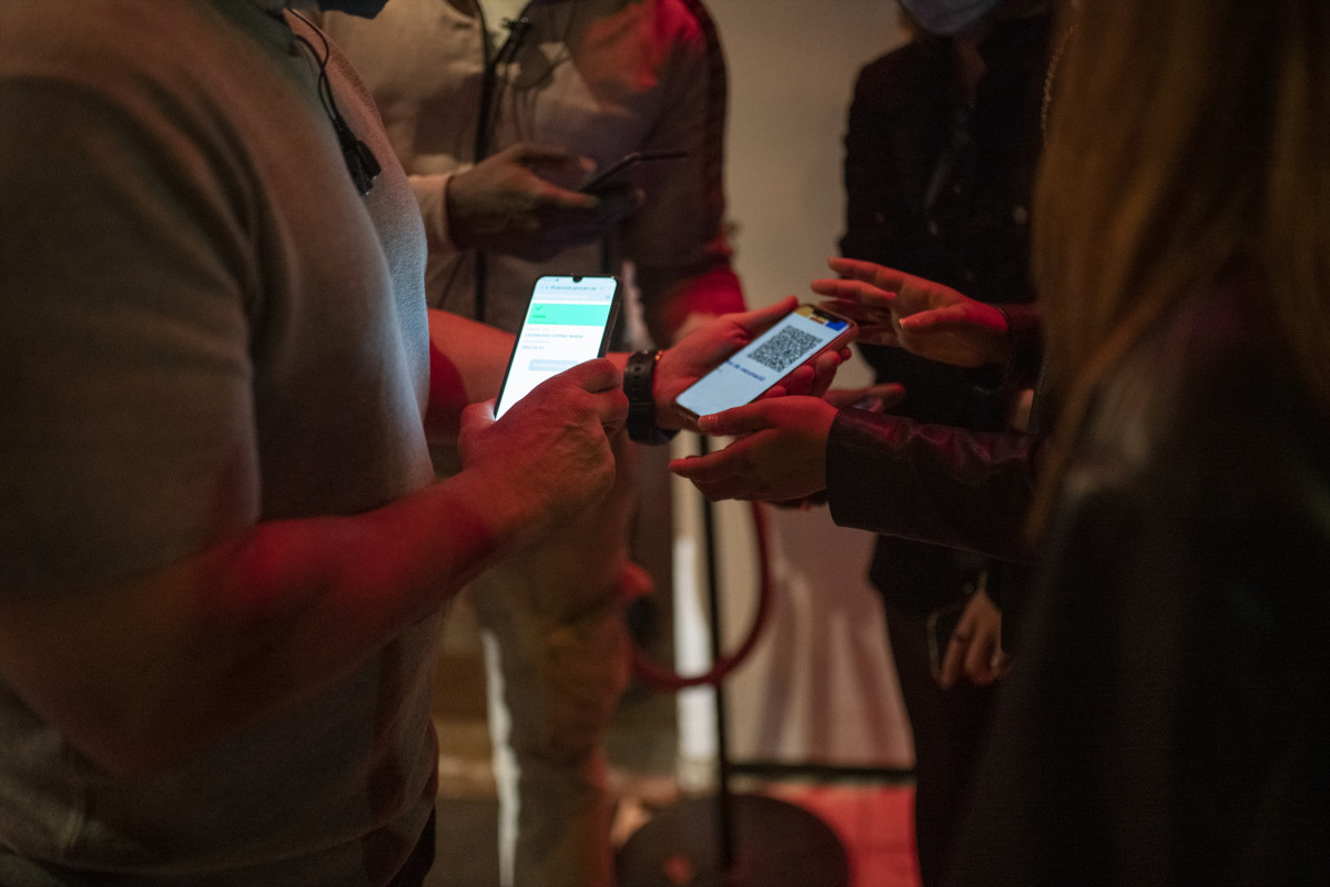 Una persona mostra un codi QR per entrar a un local d'oci nocturn la mateixa nit en què entra en vigor la reobertura en interiors a mitjanit, a 8 d'octubre de 2021, a Barcelona, Catalunya (Espanya).