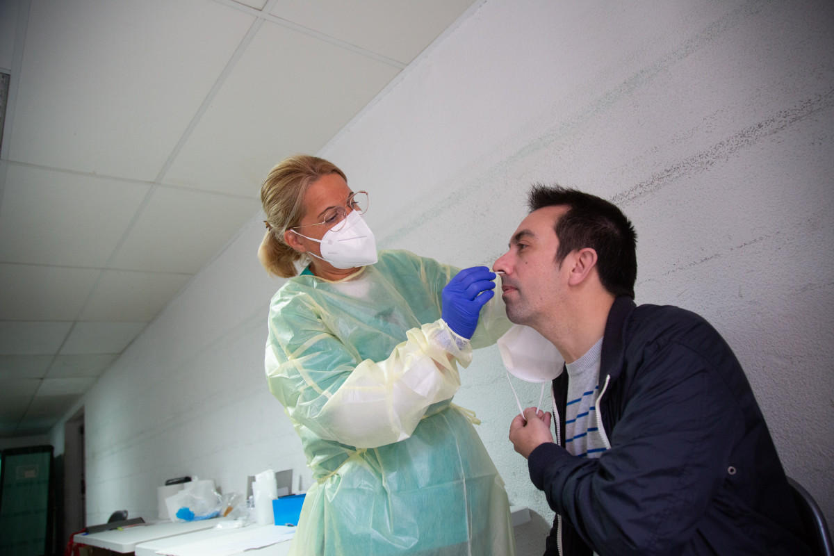Arxiu - Una sanitària fa un test d'antígens o una PCR a un home.