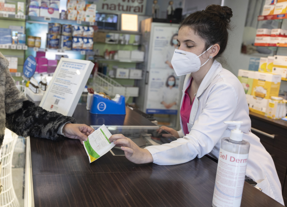 Una farmacèutica mostra un test d'antígens a una persona a la farmàcia 'Las Bessones', a 10 de gener de 2022, a Madrid (Espanya). El president del Govern, ha anunciat que el Govern té previst controlar els preus dels tests q