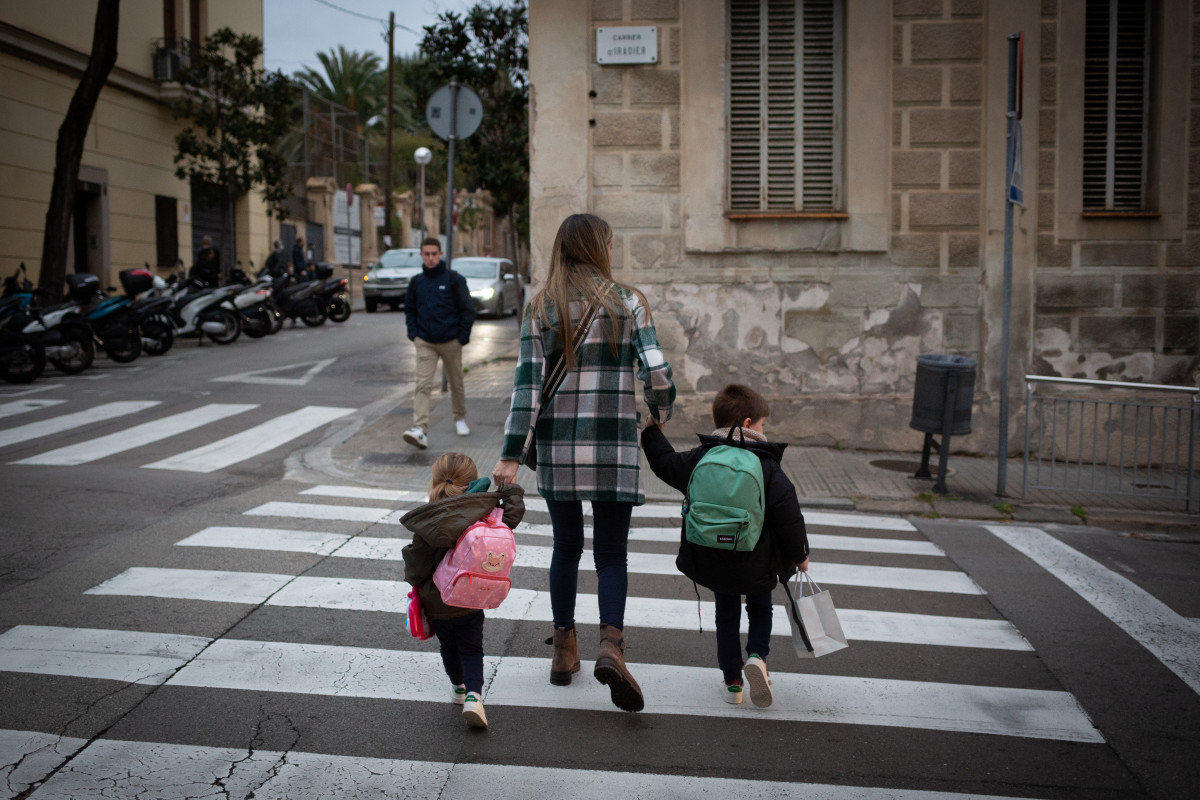 Archivo - Dos niñas de la mano con una mujer a su llegada a clase