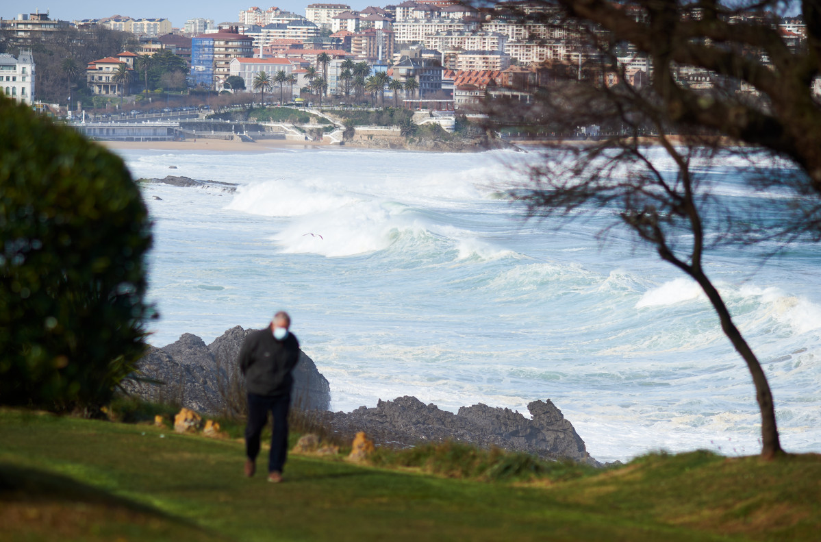 Una personas camina cerca de la playa donde se puede observar el fuerte oleaje, a 25 de febrero de 2022, en Santander, Cantabria (España). La Agencia Estatal de Meteorología (AEMET) ha activado la alerta naranja por fenómenos costeros para el día de hoy e