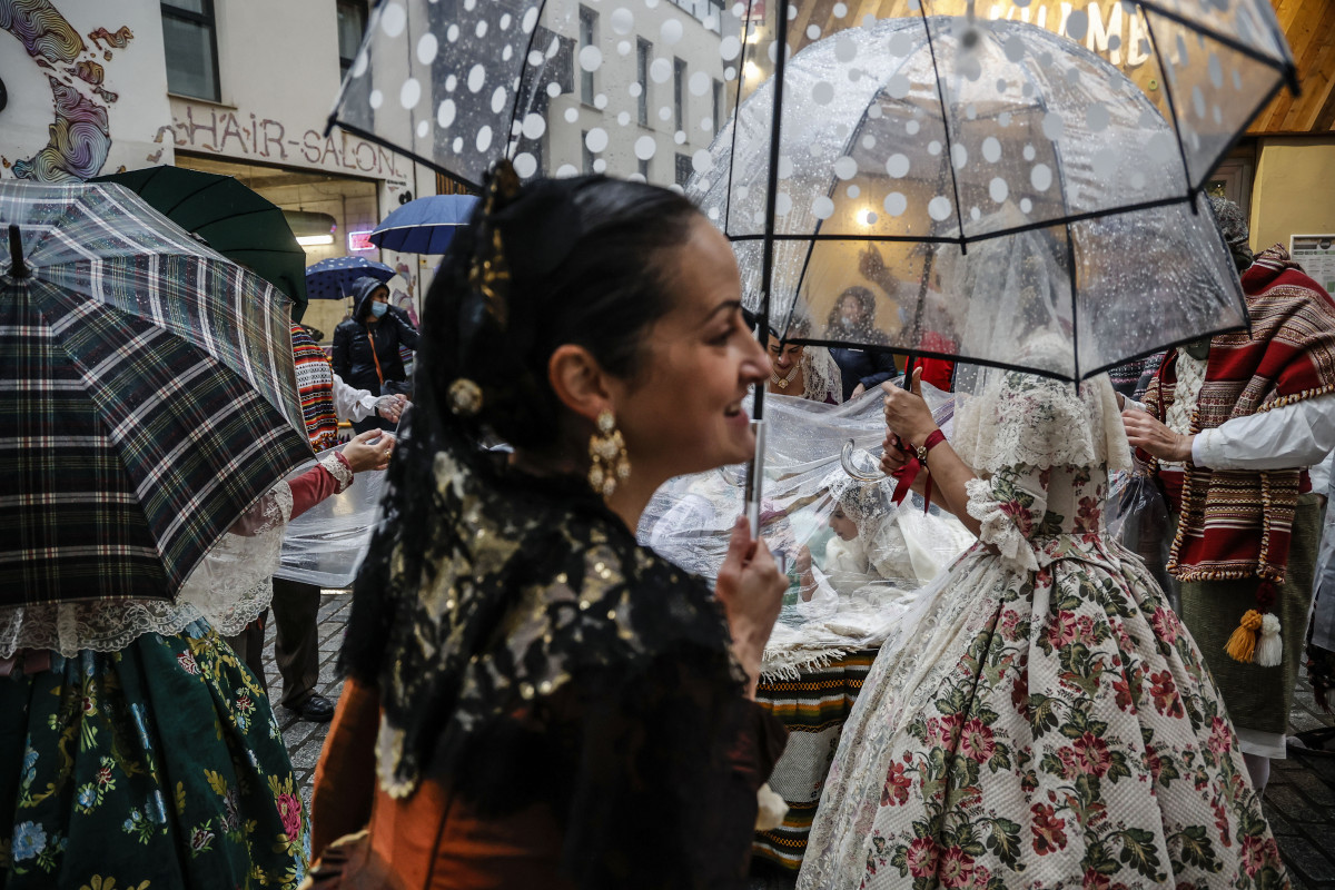 Una fallera se cubre con un paraguas en la ofrenda floral a la Virgen de los Desamparados, a 17 de marzo de 2022, en Valencia, Comunidad Valenciana (España). La Junta Central Fallera ha decidido celebrar el desfile de esta tarde, pese al temporal de lluvi