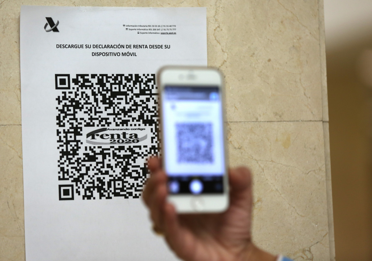 Una persona mostra un codi QR amb què accedir a la declaració de la Renda 2020 dins d'una oficina de l'Agència Tributària