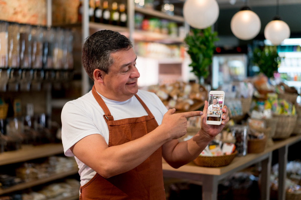L'amo d'una pime d'alimentació mostra al vostre smartphone un sistema per vendre online els seus productes