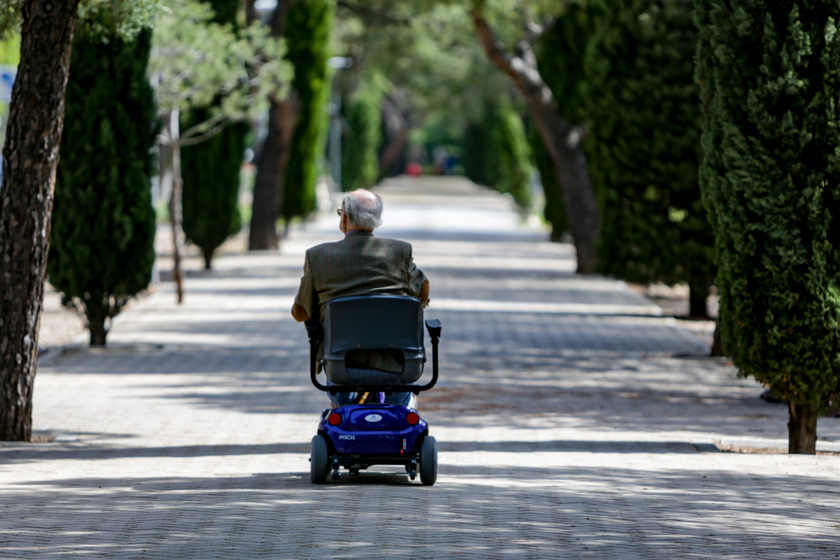 Arxiu - Un ancià amb cadira de rodes elèctrica en un parc a Madrid.