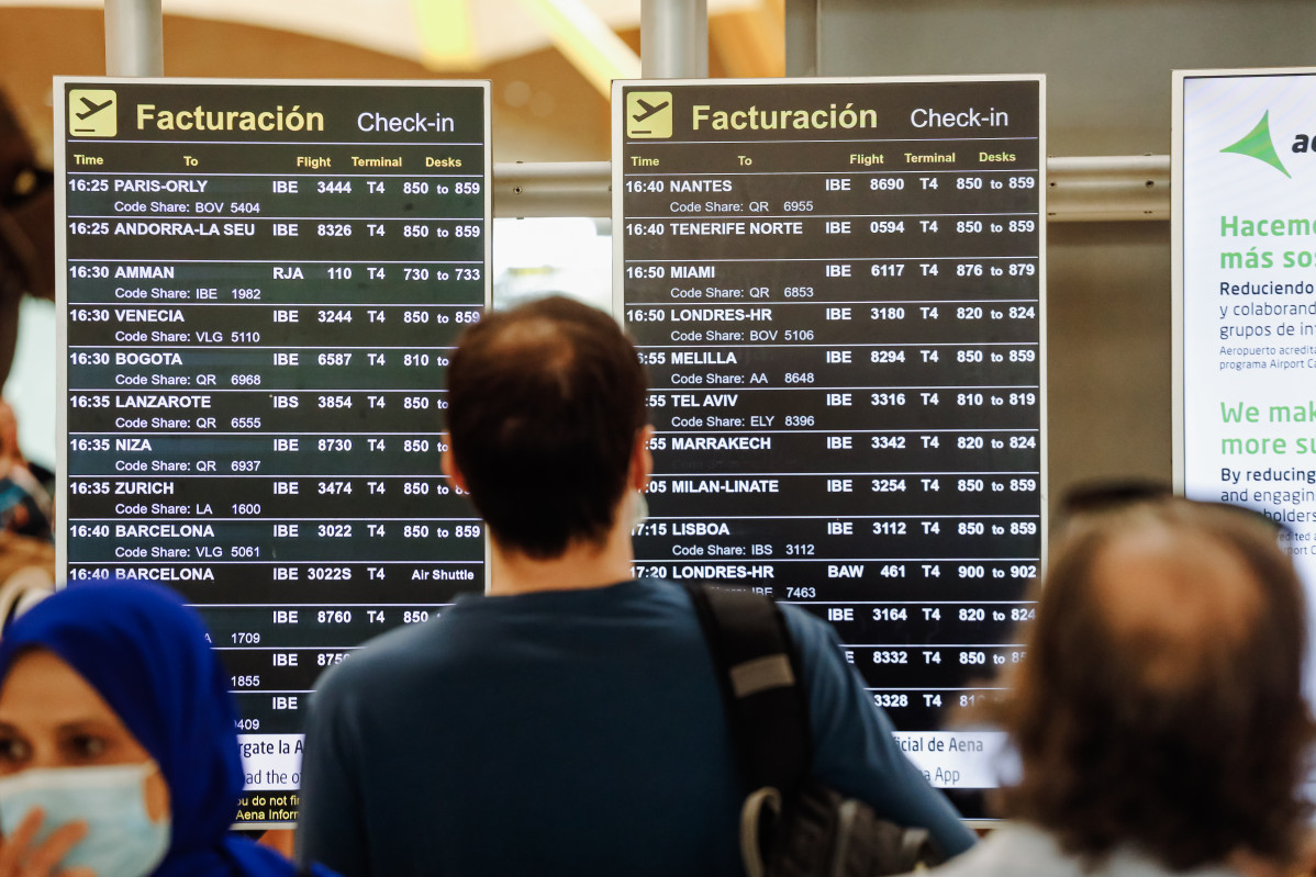 Passatgers observen les pantalles amb els vols de la Terminal 4 de l'Aeroport Adolfo Suárez Madrid Barajas, a 1 de juliol de 2022, a Madrid (Espanya).