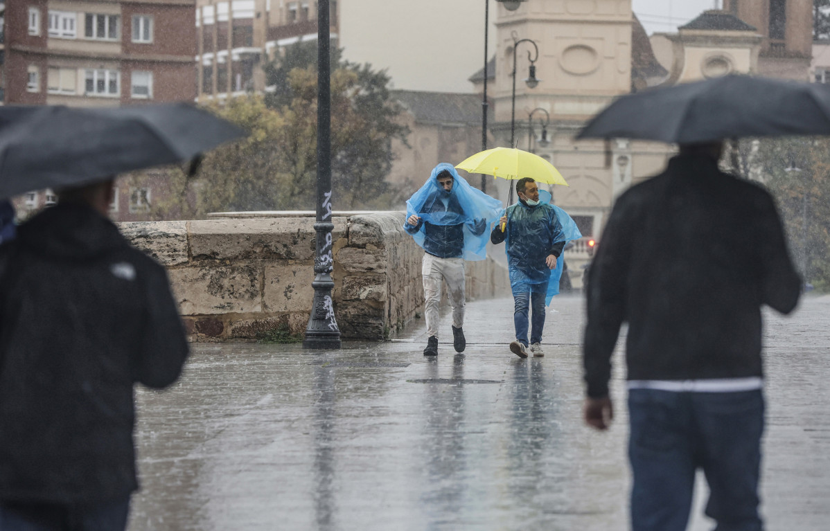 Arxiu - Dues persones amb paraigües i impermeables caminen sota la pluja, a 3 de maig de 2022, a València, Comunitat Valenciana (Espanya). València està registrant la primavera més humida al segle i mig --amb dades des del 1864-- i les pluges d'avui ha