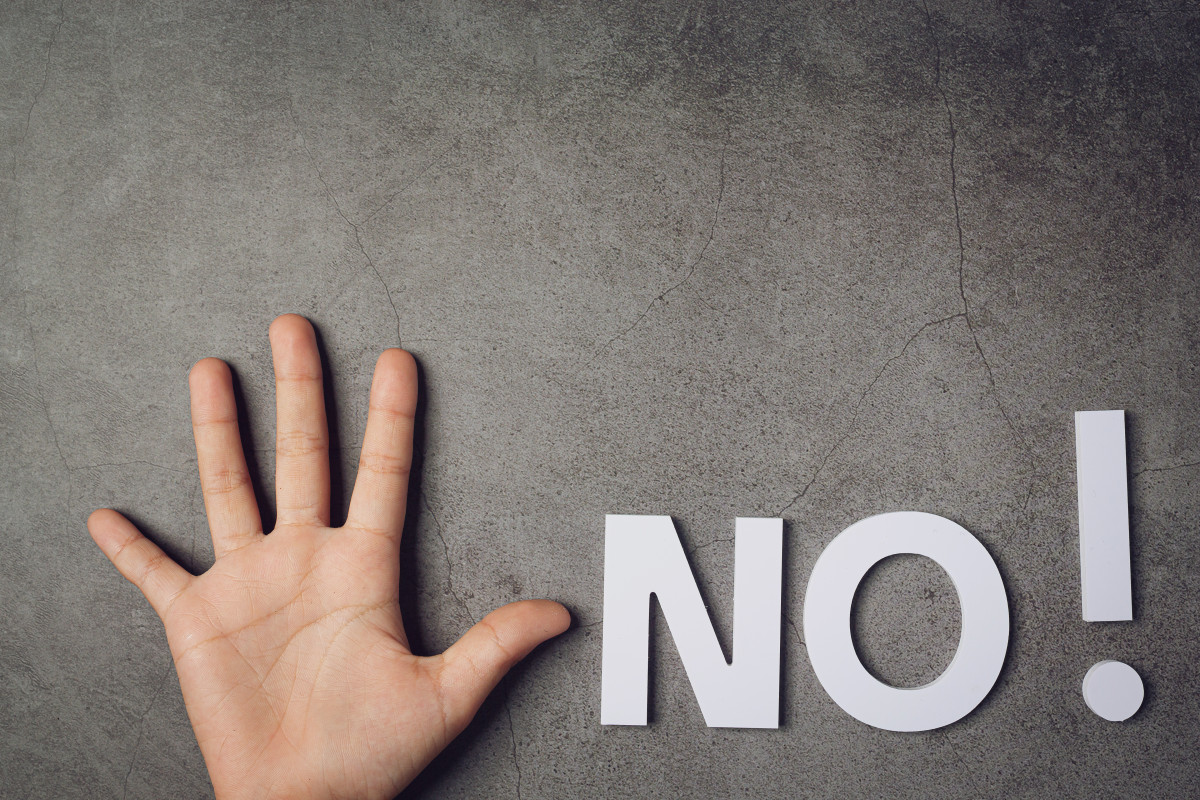Word no with child s hand on dark wall