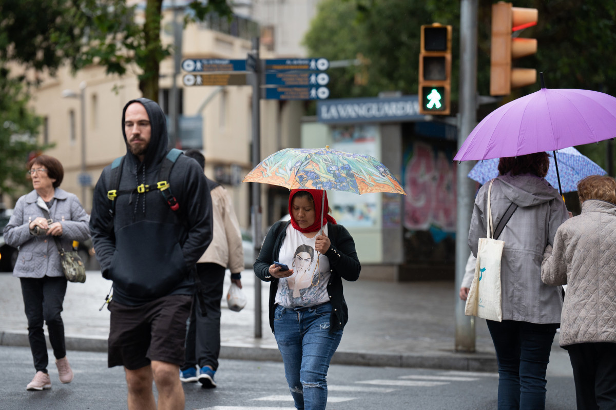Diverses persones amb paraigües passegen per un dels carrers de la ciutat, el 12 de maig de 2023, a Barcelona, Catalunya (Espanya).
