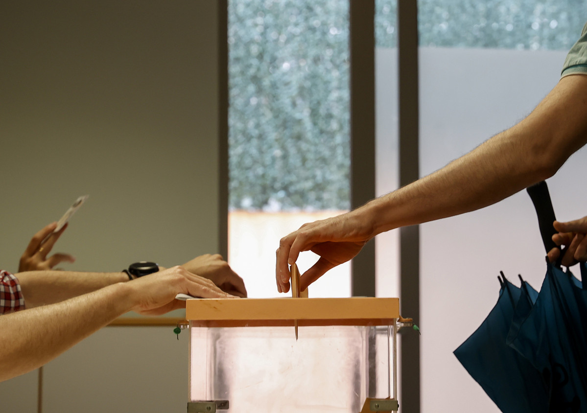 Una persona fica el vot en una urna