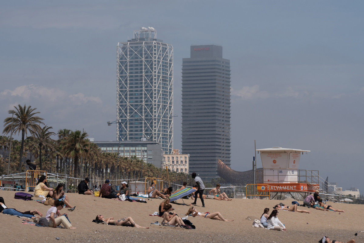 Arxiu - Diverses persones prenen el sol a la platja de la Barceloneta aquest estiu