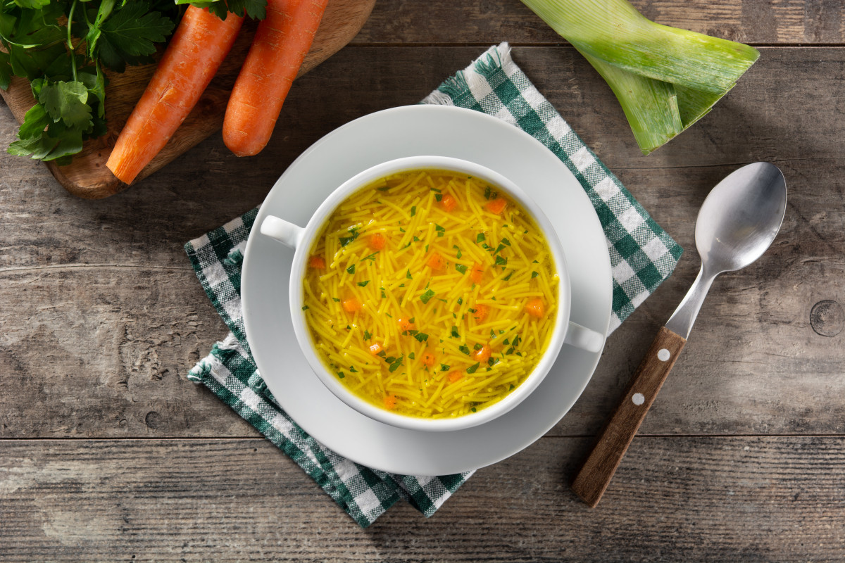 Sopa pollastre fideus bol blanc sobre taula fusta