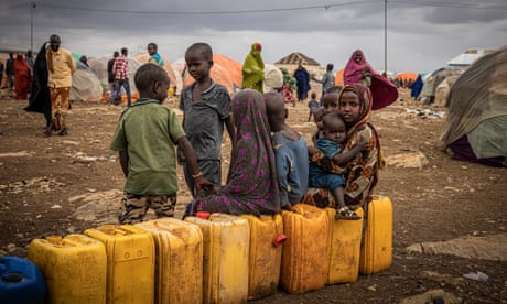 Nens asseguts en ampolles d'aigua esperant a ser omplert entre tendes de campanya en un campament de desplaçats per a persones afectades per la sequera a Baidoa, Somàlia.